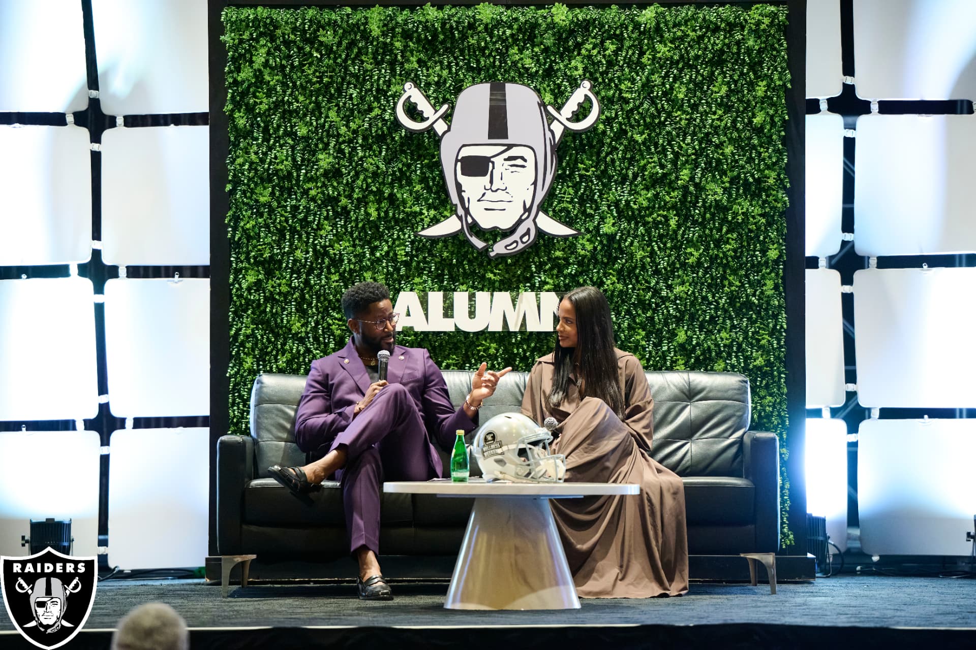 Two speakers seated on stage at a Raiders alumni wellness event
