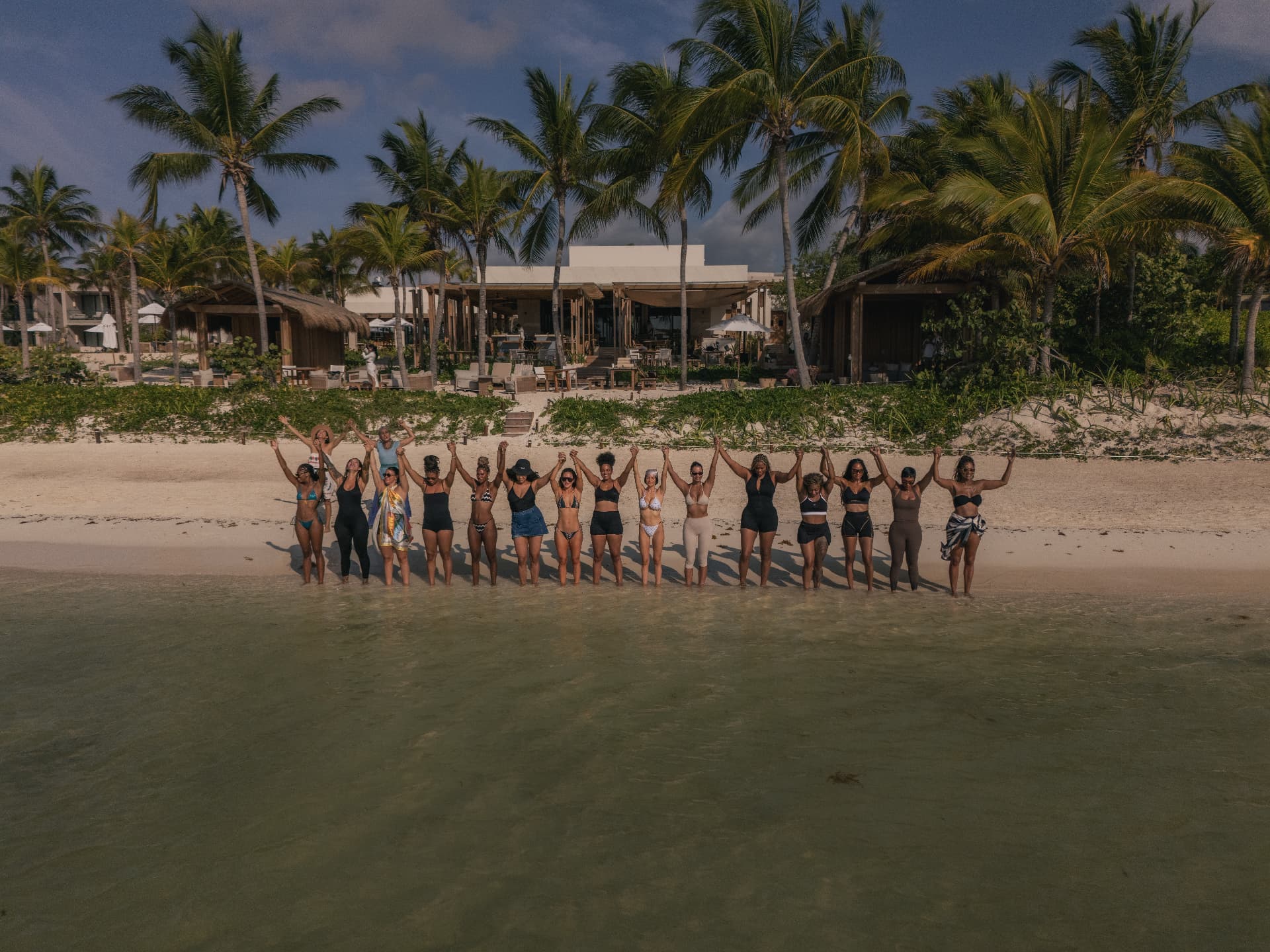 Ambassadors holding hands along the shoreline at sunrise